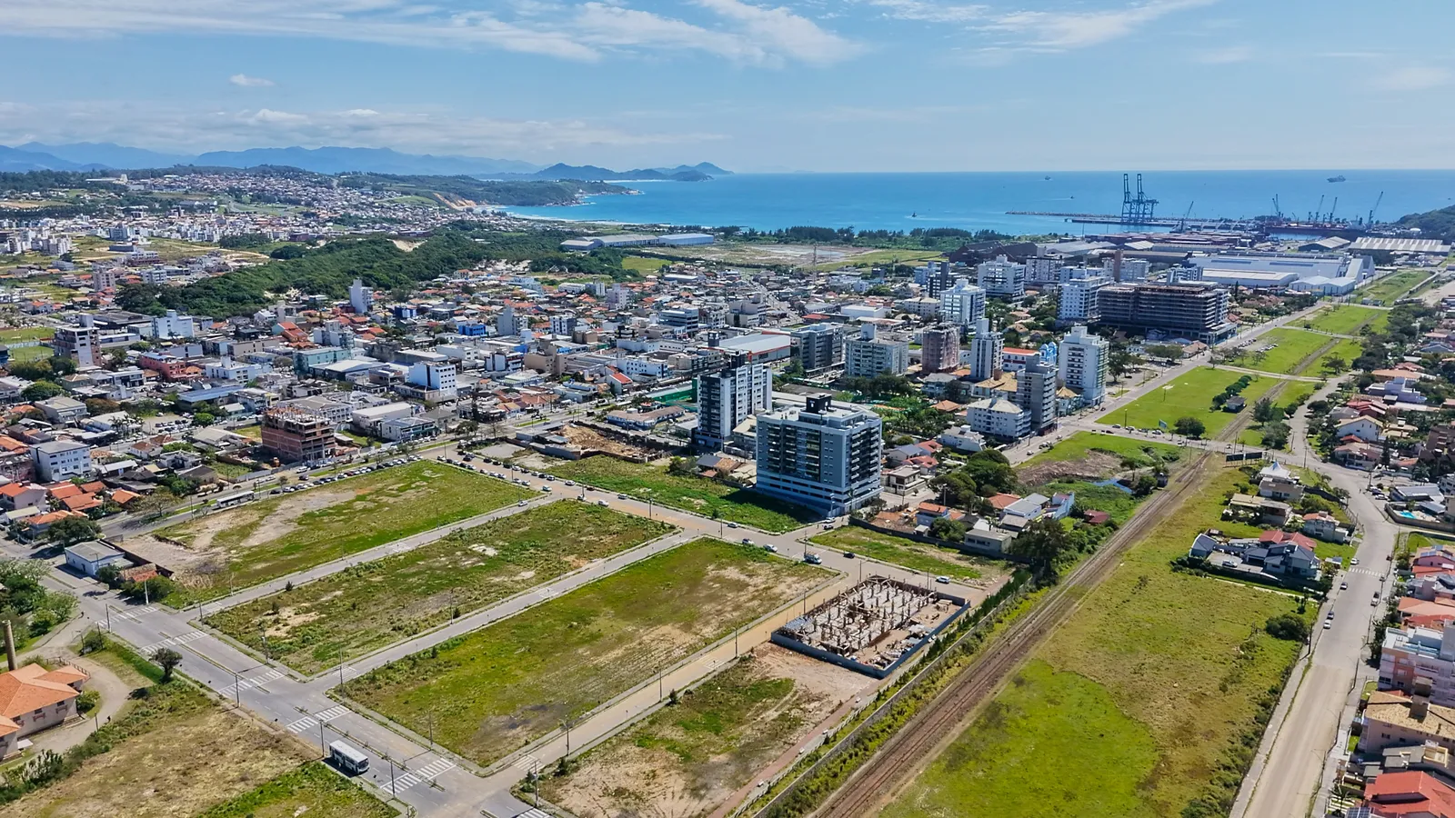 Vista aérea do centro do bairro, com quadras, comércio e o mar ao fundo.